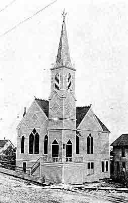 Two story frame building with gables; two sets of double doors; four story bell-tower.