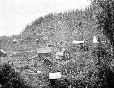 Hillside clearing with scattered one and two-story buildings, some fences.